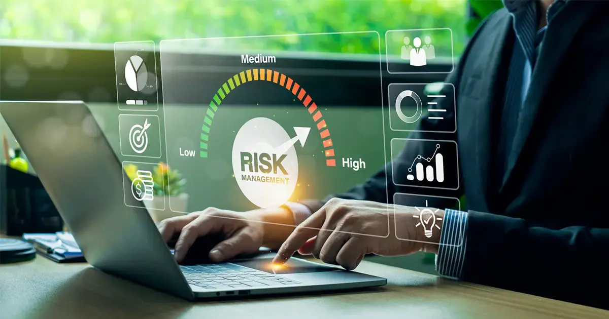 Professional using a laptop with a digital risk management dashboard showing low-to-high risk indicators.