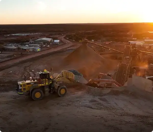 Mining loader working at a site during sunset with processing plant in background