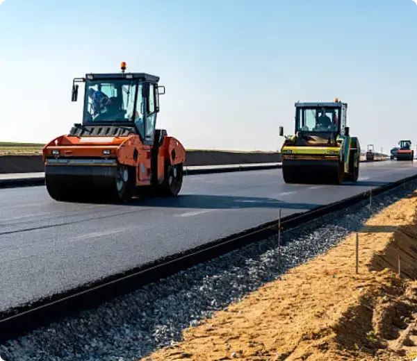 Road rollers paving new asphalt highway under clear sky