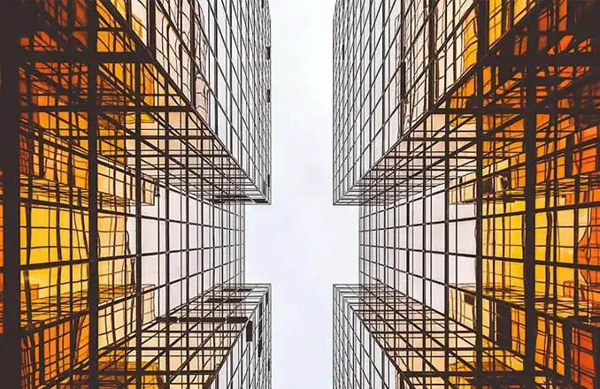 Upward view of orange glass skyscrapers symbolising transparency and modern infrastructure management.