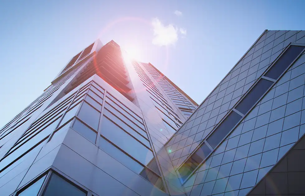 Modern commercial building exterior viewed from below, representing corporate finance and executive discussions.